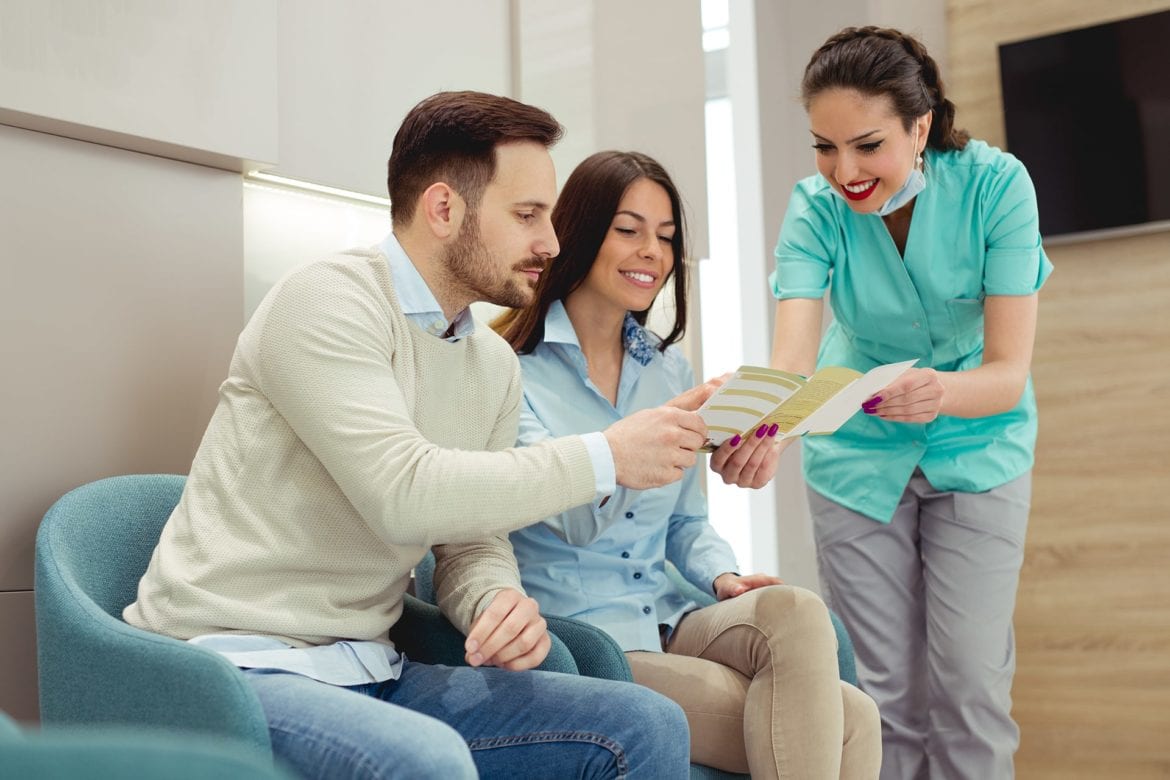 A young couple is going over paper work with dental staff.