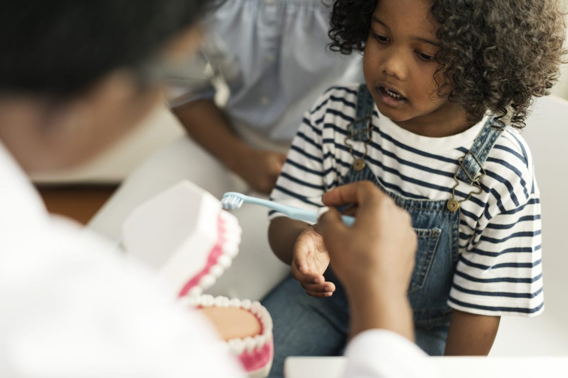 Little girl being shown how to brush her teeth