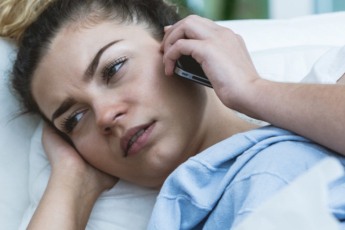 A woman lying in bed while making a phone call