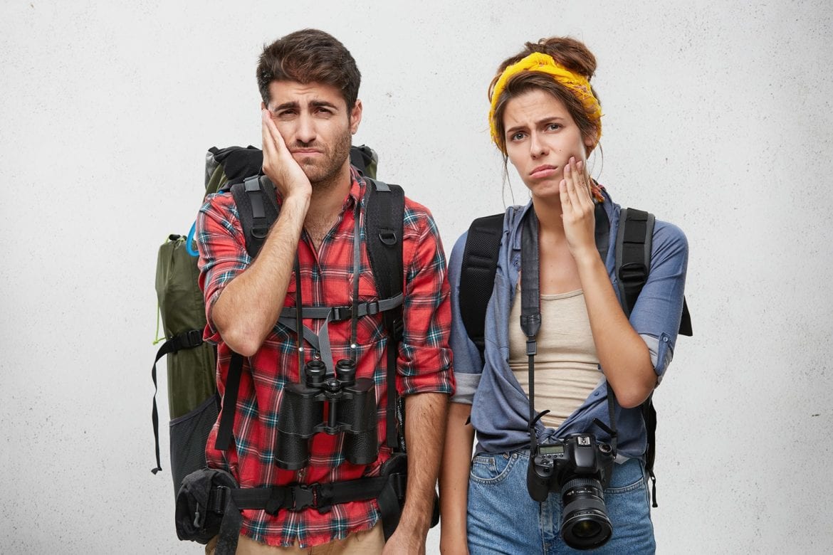 A man and a woman are holding the sides of their mouths because of tooth pain.