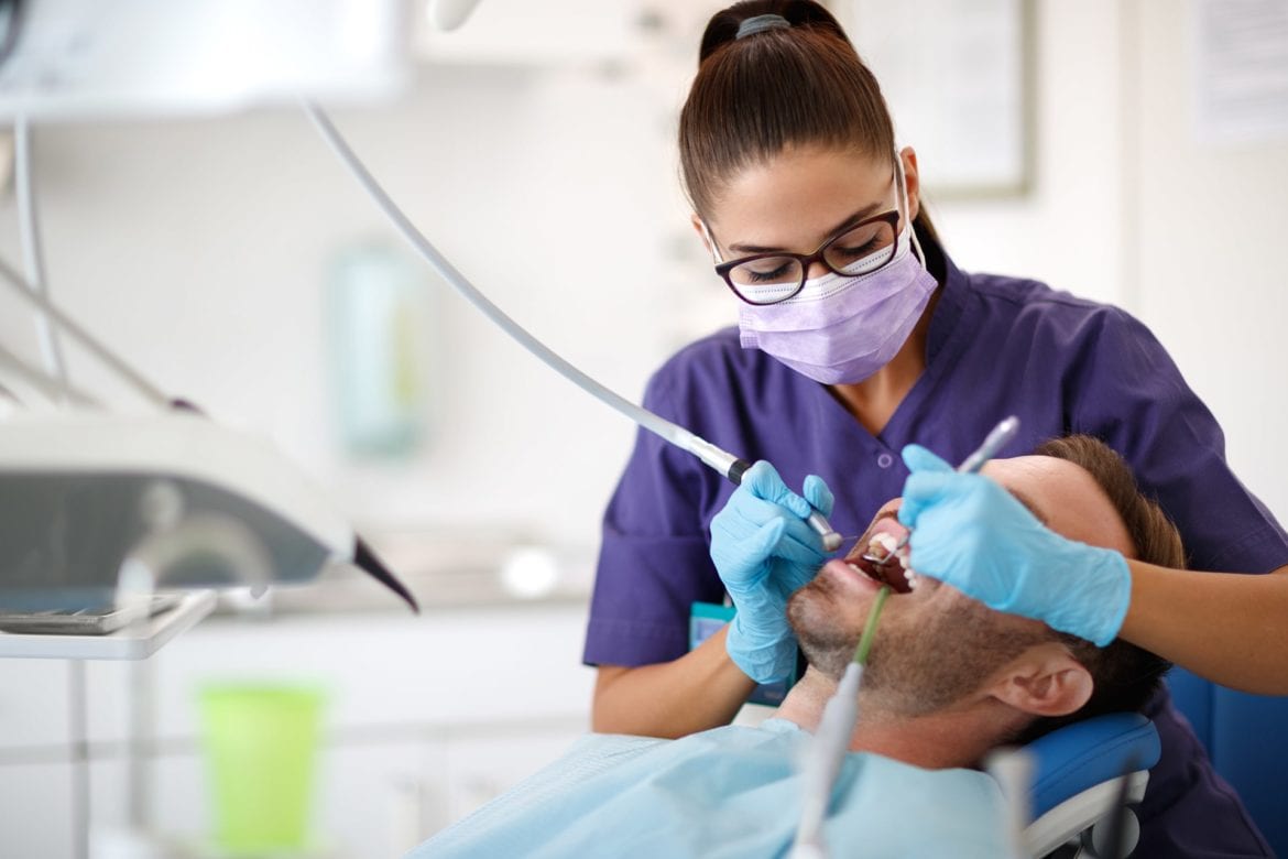 Dental hygienists cleaning male penitents teeth