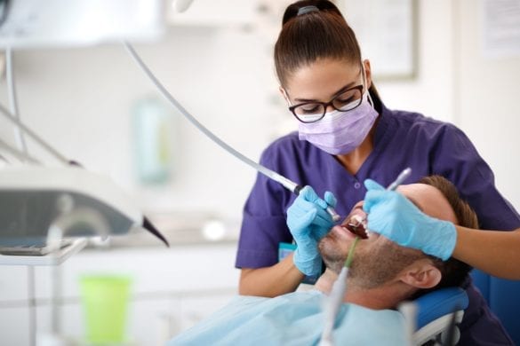 Dental hygienists cleaning male penitents teeth
