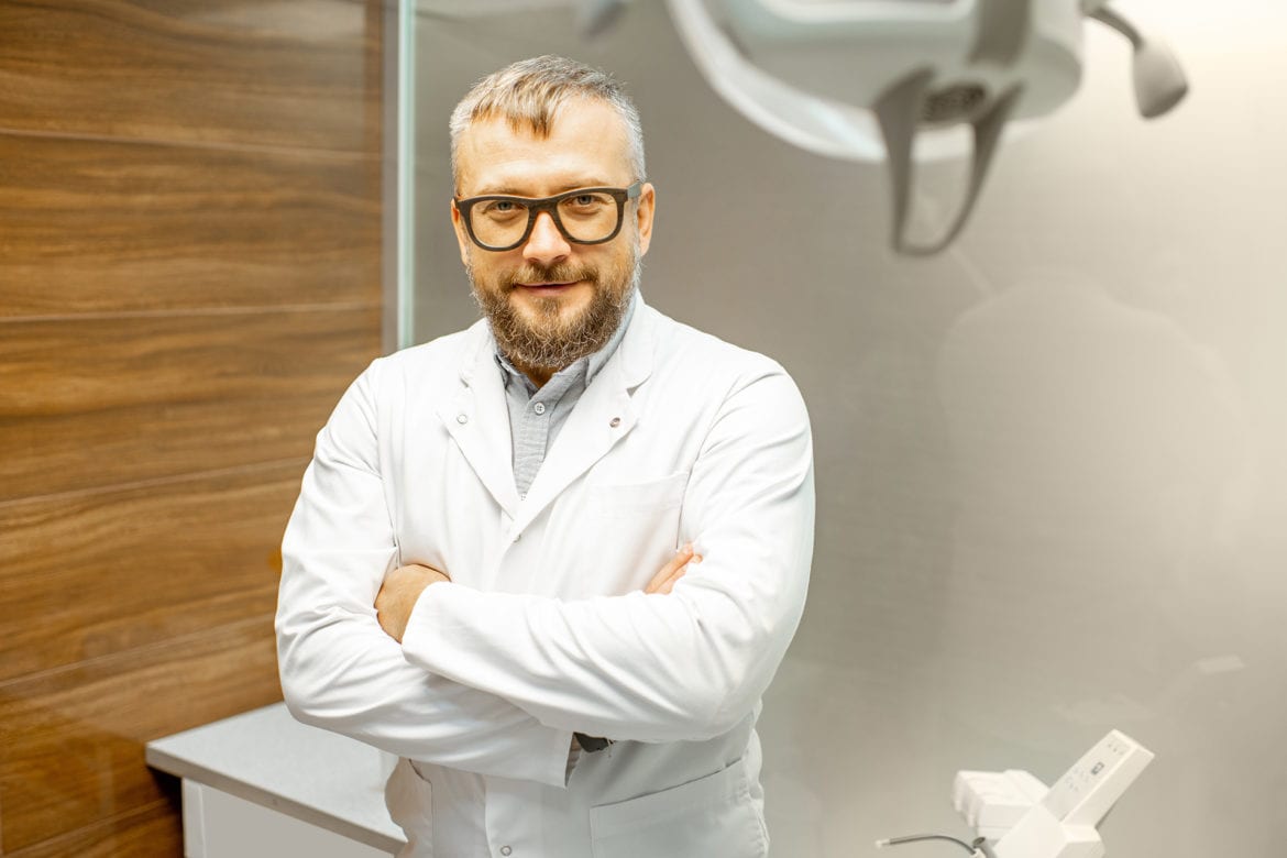 Negative emotion. Woman having tooth ache. Dentist standing with folded arms