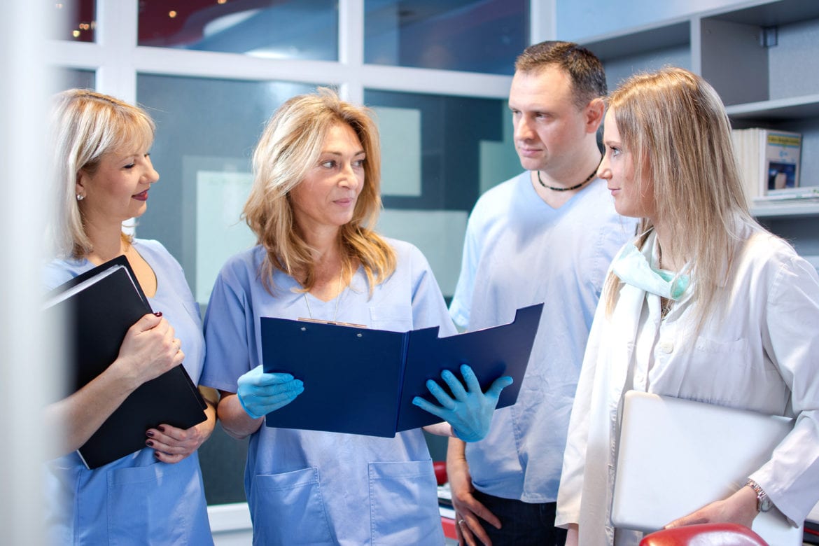dentist and staff looking at paper work within a blue folder