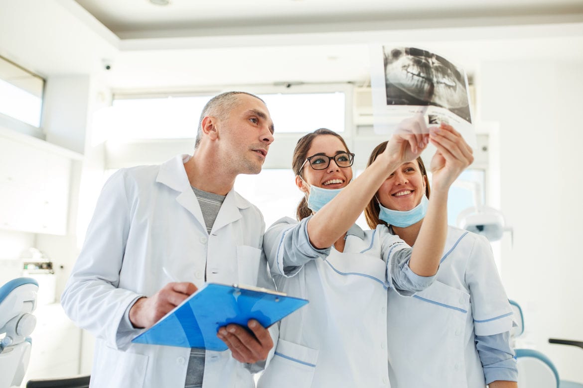 Dentist and staff look at tooth x-rays