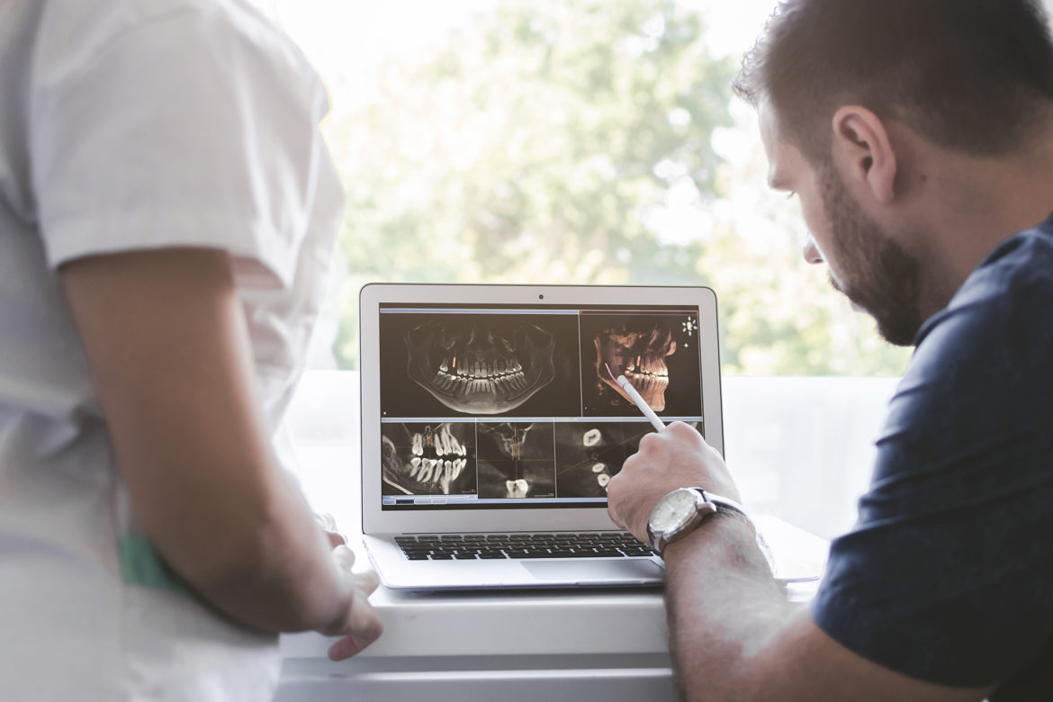 blog-eds-dsonewtech dentist examining a tooth x-ray with an assistant