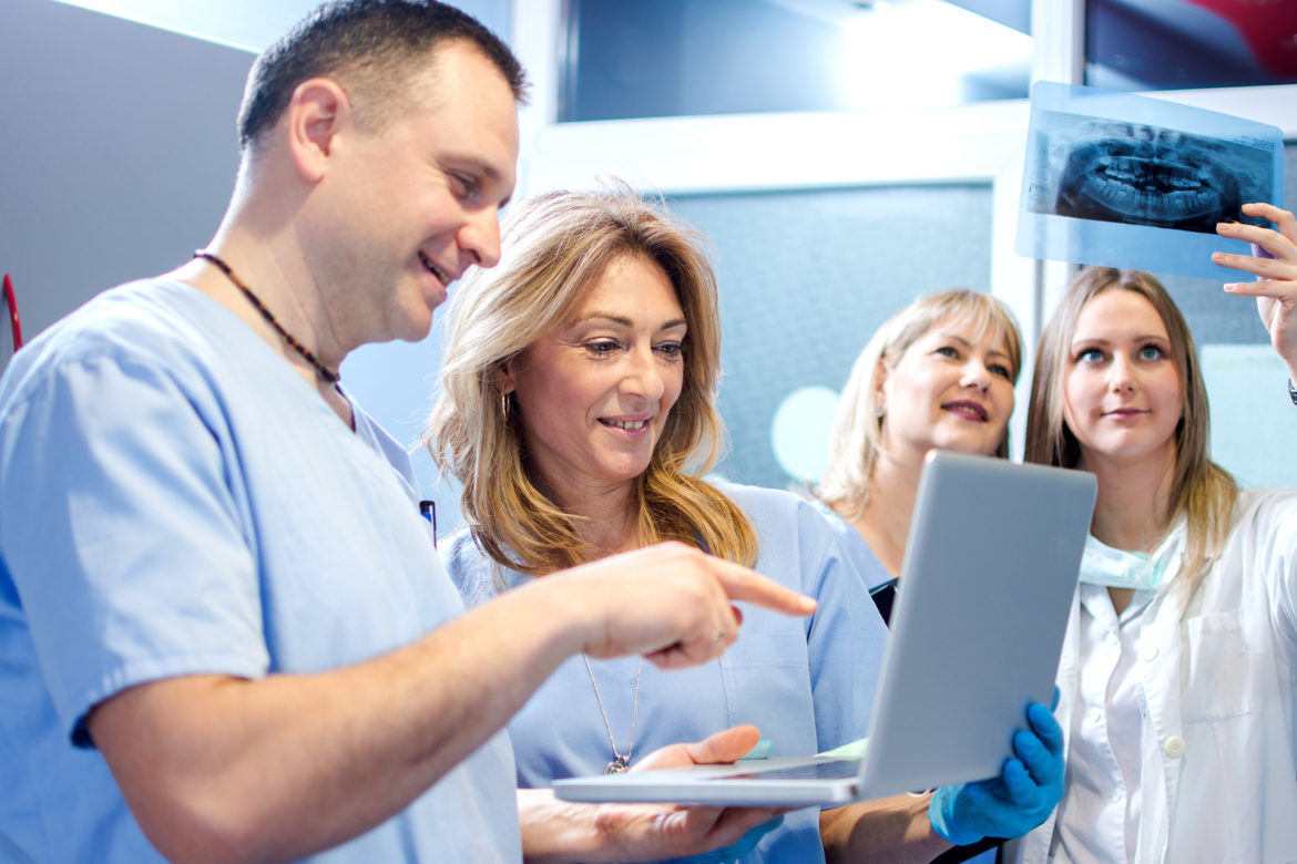 blog-eds-solopractice dentist and his staff looking at a laptop