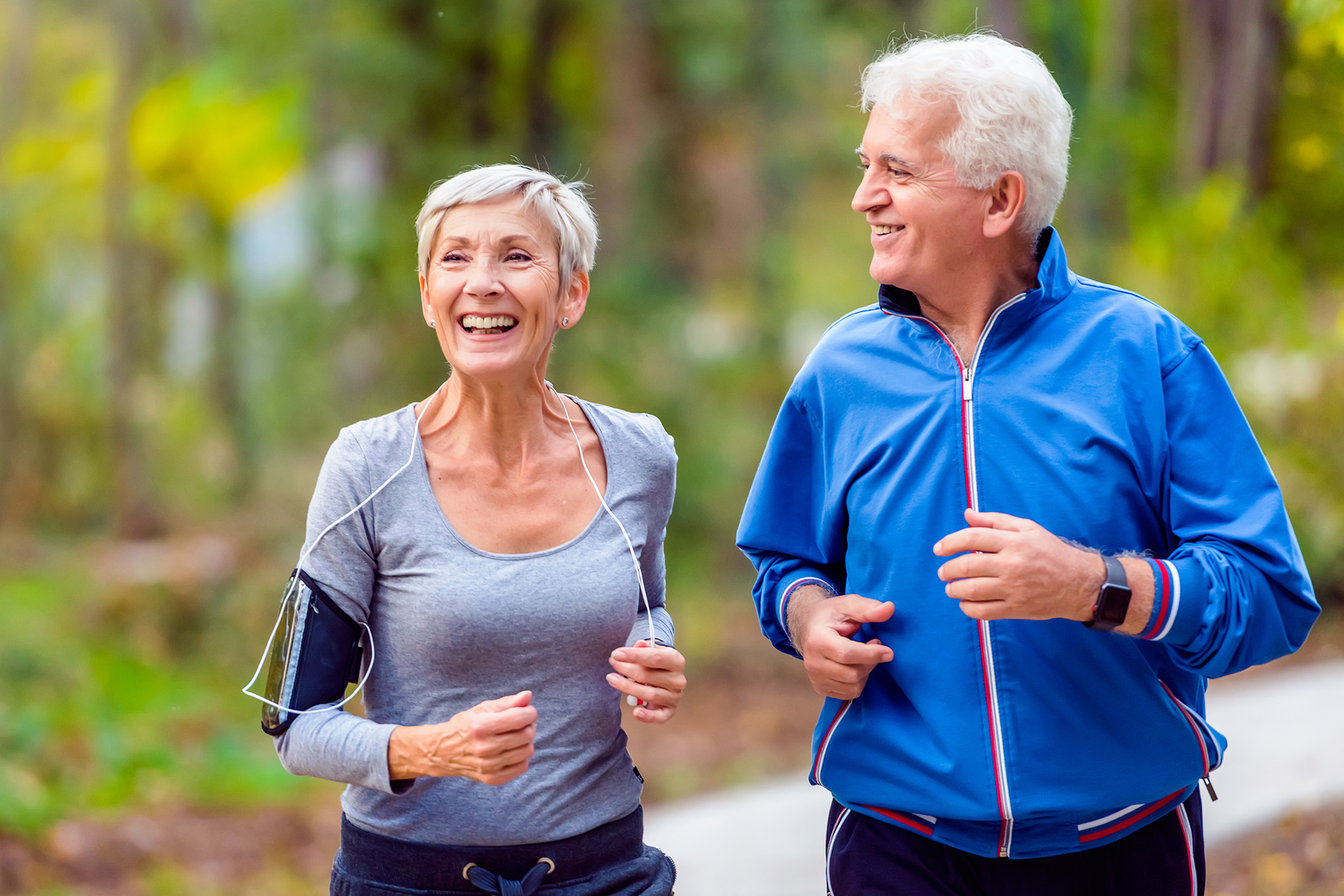 elderly couple smiling and jogging outside.