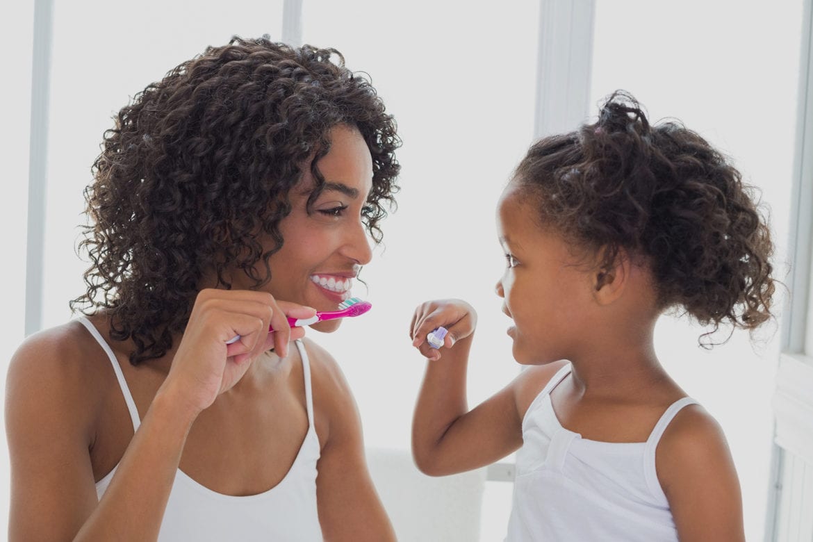 Mother and daughter brushing their teeth