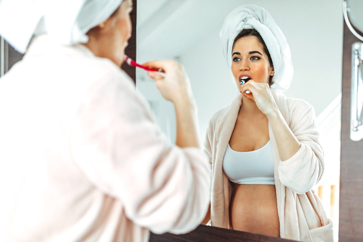 woman brushing teeth while looking into the mirror