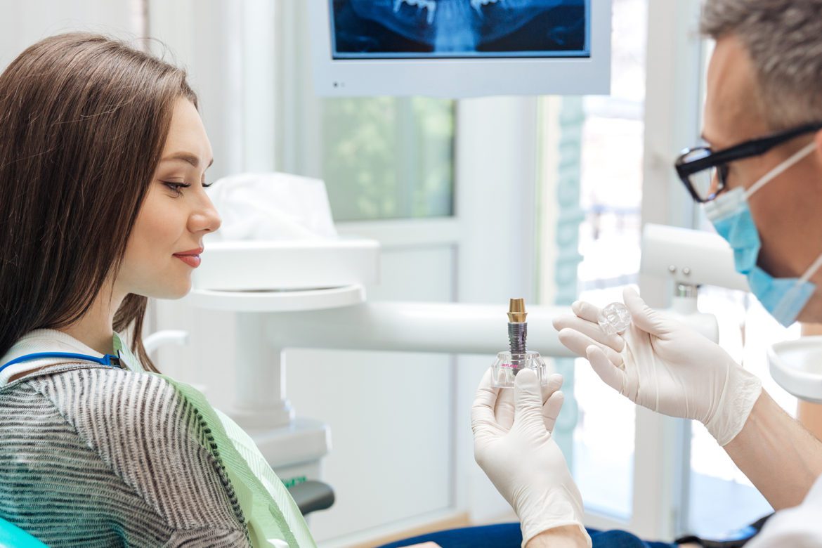 dentist and patient looking at dental implatant 