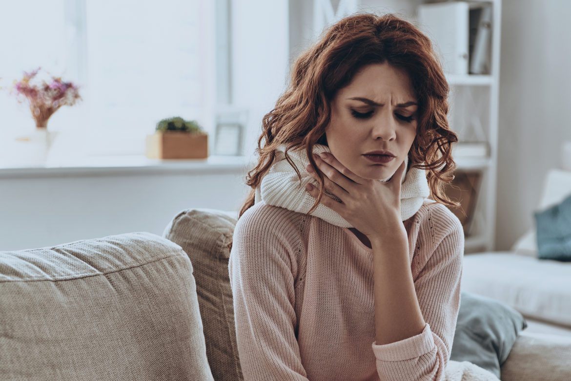 Woman holding her throat while experiencing pain.