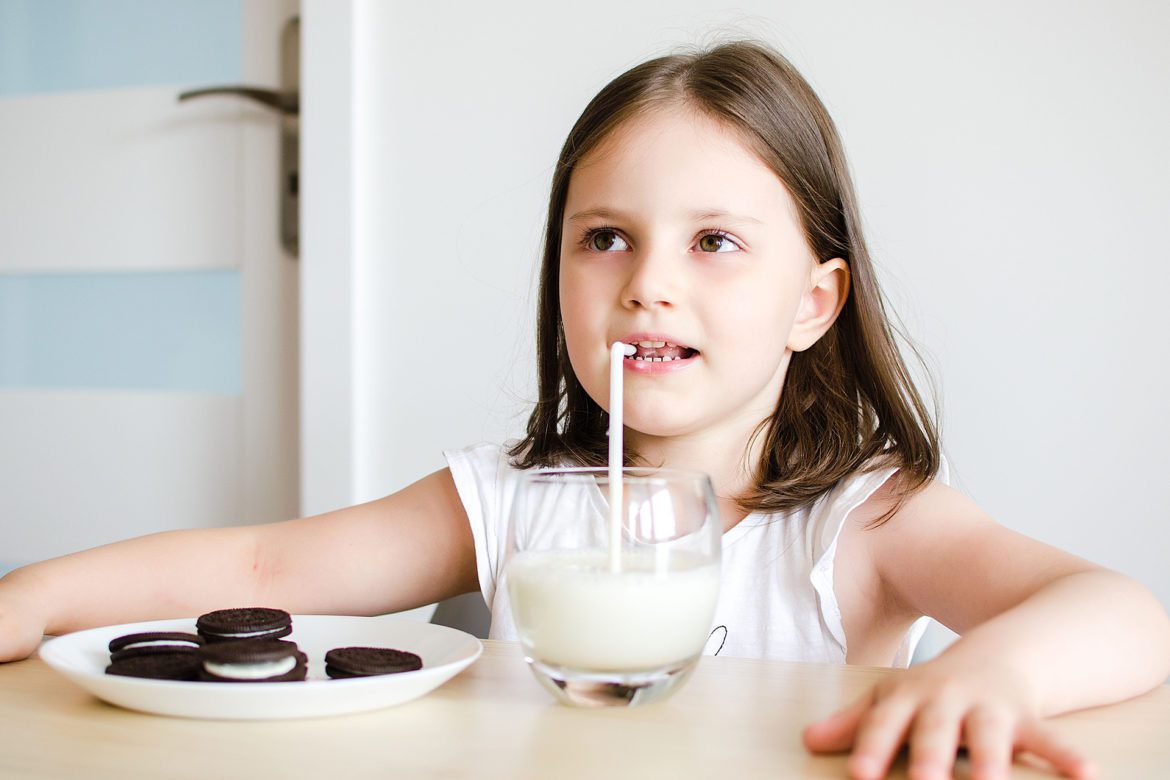 A little girl with oreos and a glass of milk