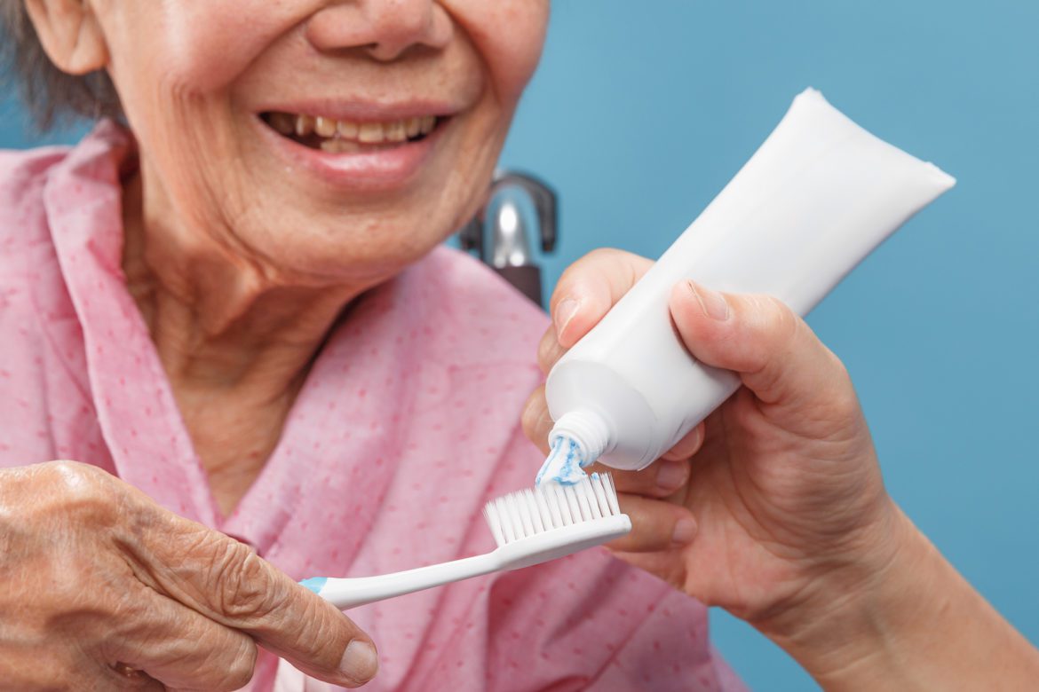 woman applying tooth paste to her toothbrush