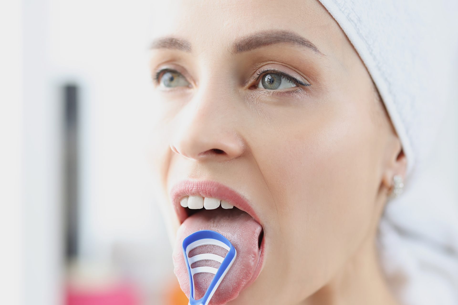 Woman using a tongue scraper