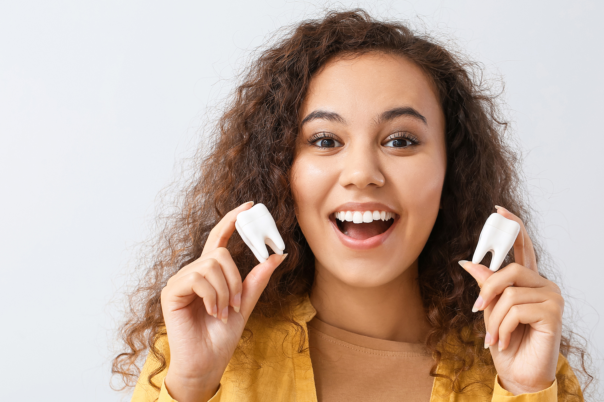 Woman holding two singular white tooth models