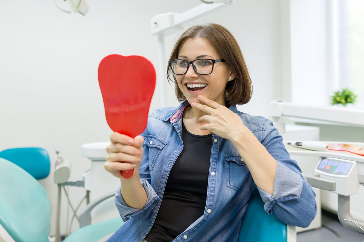 Woman smiling and holding red hand mirror