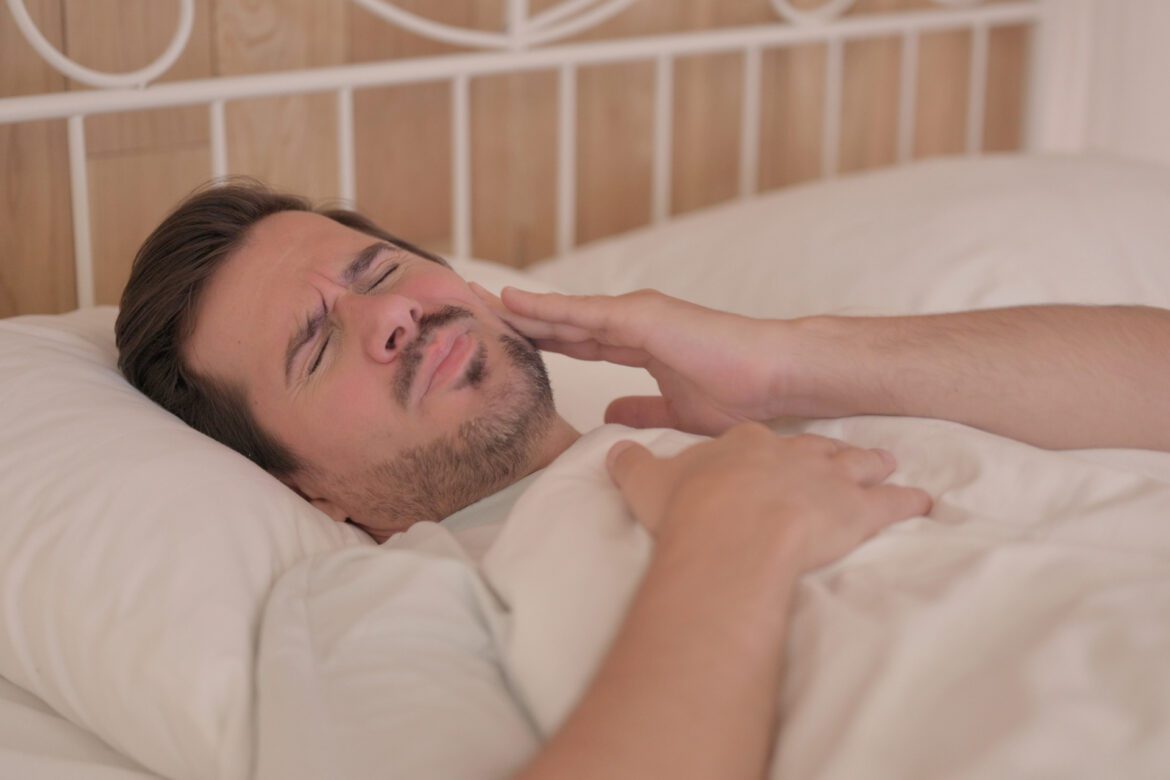 eds - man in bed suffering tooth pain